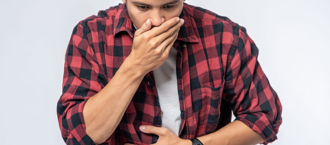 A man standing with a stomachache Put your hands on your stomach and cover your mouth.